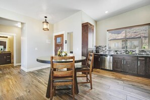 A kitchen with a round dining table, wooden chairs, and a built-in oven. - Comfortable Moab Condo with Patio and Views - Close to Arches and Downtown (Moab)