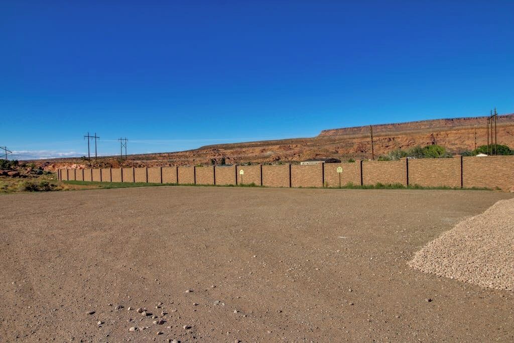 Una zona pavimentada con un muro de ladrillo y postes de servicios.