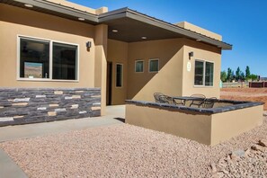 A building with a stone facade, large windows, and a patio area with outdoor seating. - Comfortable Moab Condo with Patio and Views - Close to Arches and Downtown (Moab)