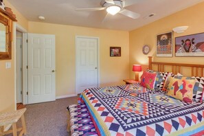 A bedroom with a bed, a ceiling fan, a door, and a nightstand with a lamp. - Condo Surrounded by Natural Red Rock Beauty with Seasonal Pool Access (Moab)