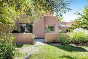 A modern building with large windows and a well-maintained garden. - Condo Surrounded by Natural Red Rock Beauty with Seasonal Pool Access (Moab)