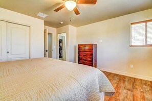 Quarto com cama, ventilador de teto, guarda-roupa e janela.