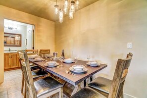 Ein Esszimmer mit einem langen Tisch, gedeckt für sechs Personen, Holzstühlen und einem Kronleuchter.