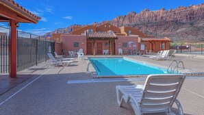Hotel med swimmingpool, udendørs siddepladser og udsigt til røde klippeformationer.