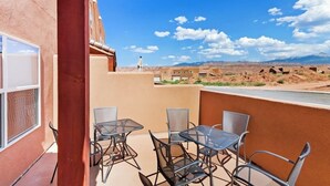 En balkon med udendørs møbler og udsigt over et ørkenlandskab.
