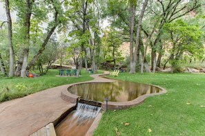 Ein angelegter Garten mit Teich, Wasserfall und Sitzbereichen.
