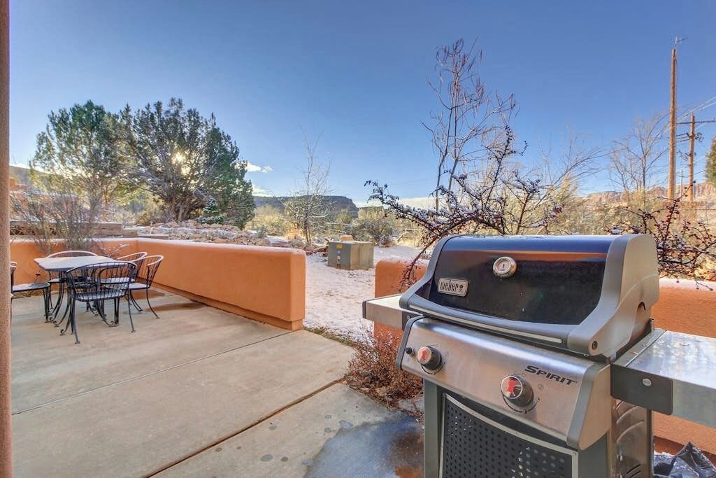 An outdoor patio with a grill, a table, and chairs.