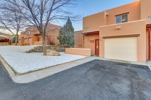 A residential property with a garage, a driveway, and a snow-covered lawn. - Golf Course Front Condo with Seasonal Pool & Views - Walk to Steel Bender Trail (Moab)