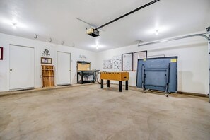 Une pièce spacieuse équipée d’un projecteur, d’un baby-foot et d’une grande armoire.