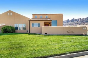 A modern building with a flat roof, a small entrance, and a clear sky in the background. - Spacious Family Friendly Home near Downtown with Seasonal Pool & Hot Tub (Moab)