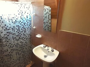 Un baño con ducha, lavabo y espejo.