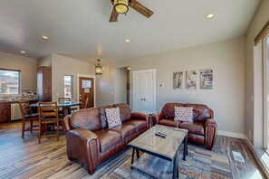 A spacious living room with leather sofas, a coffee table, and a dining area with chairs and a table. - Tranquil 2BR Mountainview Rim View with Hot Tub (Moab)