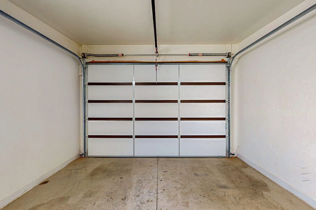 A garage with a closed door, metal shelving, and a concrete floor.
