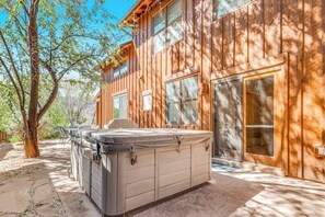 A wooden cabin with a hot tub and a covered patio area. - Mountain View Home with Private Hot Tub & Patio - Close to Golf & Trails (Moab)