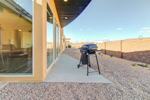 A modern house with a patio, a barbecue grill, and a clear view of the surrounding landscape. - Modern Desert Retreat in Moab with Mountain Views and Patio (Moab)