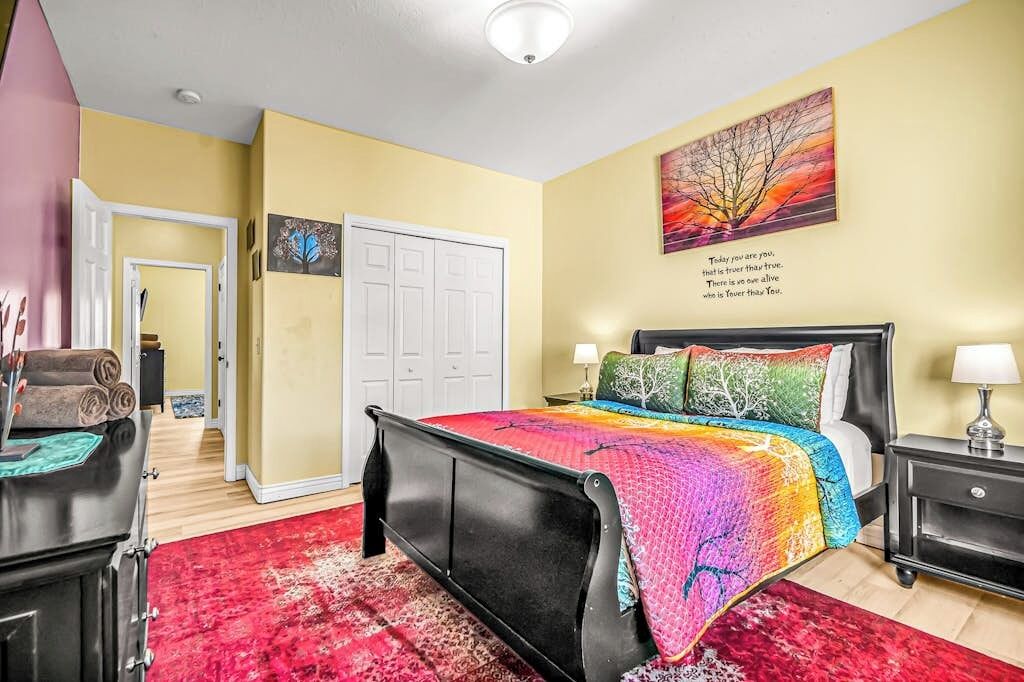 A bedroom with a bed, a nightstand, a door, and a painting on the wall.