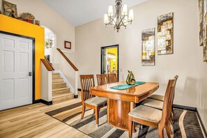 A dining area with a wooden table and chairs, a chandelier, and artwork on the walls. - Dog Friendly Moab Mountain Escape with Provate Hot Tub, Fireplace, and Game Room (Moab)