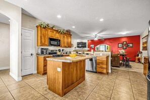 A kitchen with wooden cabinets, a microwave, and a central island. - Dog Friendly Moab Mountain Escape with Provate Hot Tub, Fireplace, and Game Room (Moab)