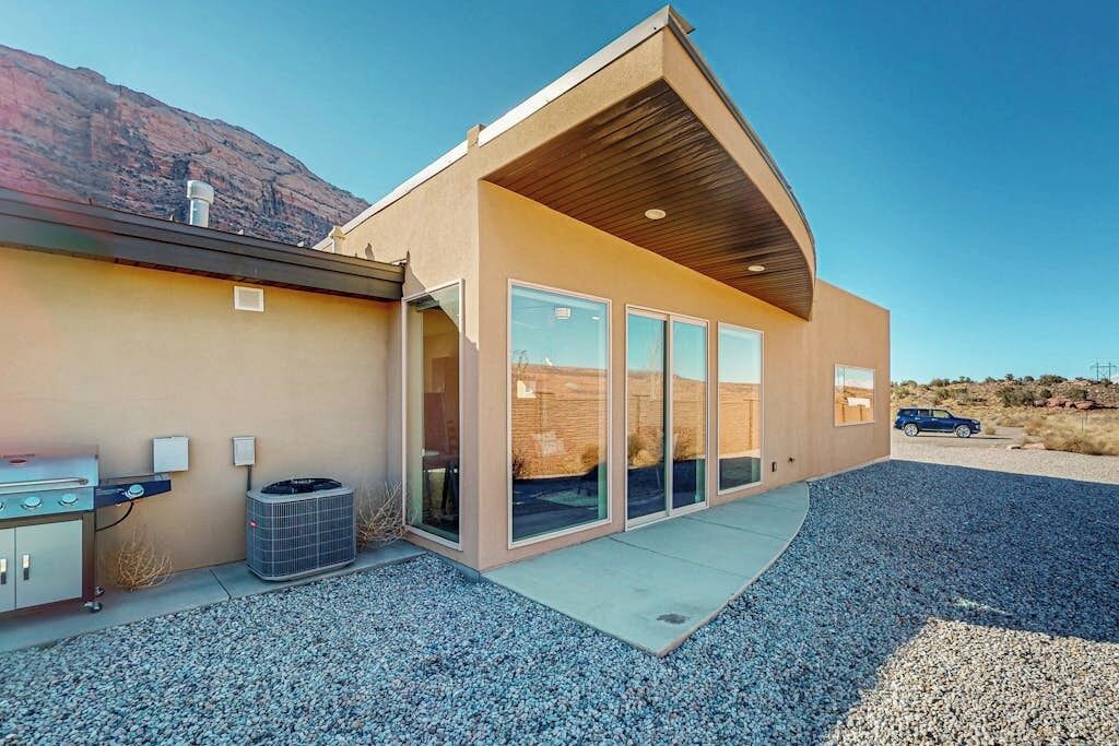 Ein modernes Haus mit großem Glasflurgang, einer überdachten Terrasse und einem Grillbereich.