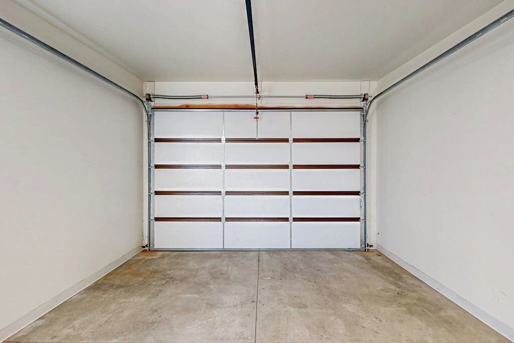 Un garaje con puerta blanca, estructura metálica y suelo de concreto.