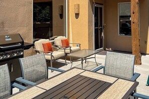 An outdoor patio with a grill, seating area, and a view of the house. - Townhome in Rim Village with Red Rock Views, Community Pool & Hot Tub (Moab)