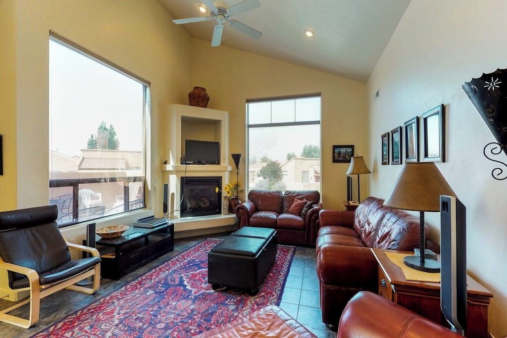A living room with a fireplace, leather sofas, a television, and a large window.