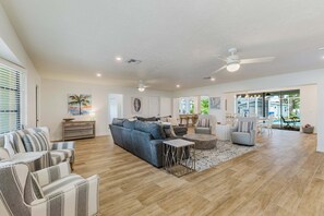 A spacious living area with a sofa, chairs, a coffee table, and a dining area with chairs and a table. - Gorgeous 4 BR, Pool Home, Game Room, Canal View, Sleeps 11! (Cape Coral)