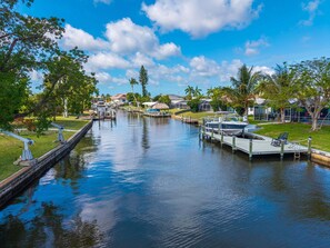 Un canal con barcos amarrados, rodeado de vegetación y casas.