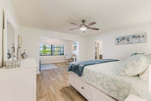 A bedroom with a bed, a desk, a chair, a ceiling fan, and a window with a view of greenery. - Gorgeous 4 BR, Pool Home, Game Room, Canal View, Sleeps 11! (Cape Coral)