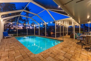 An indoor pool area with a clear view of the sky and palm trees outside. - Gorgeous 4 BR, Pool Home, Game Room, Canal View, Sleeps 11! (Cape Coral)