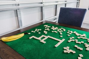 Una mesa de juego de fieltro verde con fichas de letras dispersas y un plátano encima.