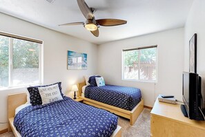 A bedroom with two beds, a ceiling fan, a television, and a window with a view of trees. - Dog-Friendly Townhome with WiFi, Nice Views & Indoor Pool (Moab)