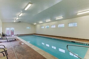 A swimming pool with a tiled deck, a few lounge chairs, and a ceiling with fluorescent lights. - Dog-Friendly Townhome with WiFi, Nice Views & Indoor Pool (Moab)