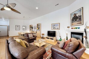 A living room with a sofa set, a television, a fireplace, and a ceiling fan. - Dog-Friendly Townhome with WiFi, Nice Views & Indoor Pool (Moab)