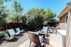 An outdoor patio with a table and chairs, surrounded by a wooden fence and trees. - Dog-Friendly Townhome with WiFi, Nice Views & Indoor Pool (Moab)