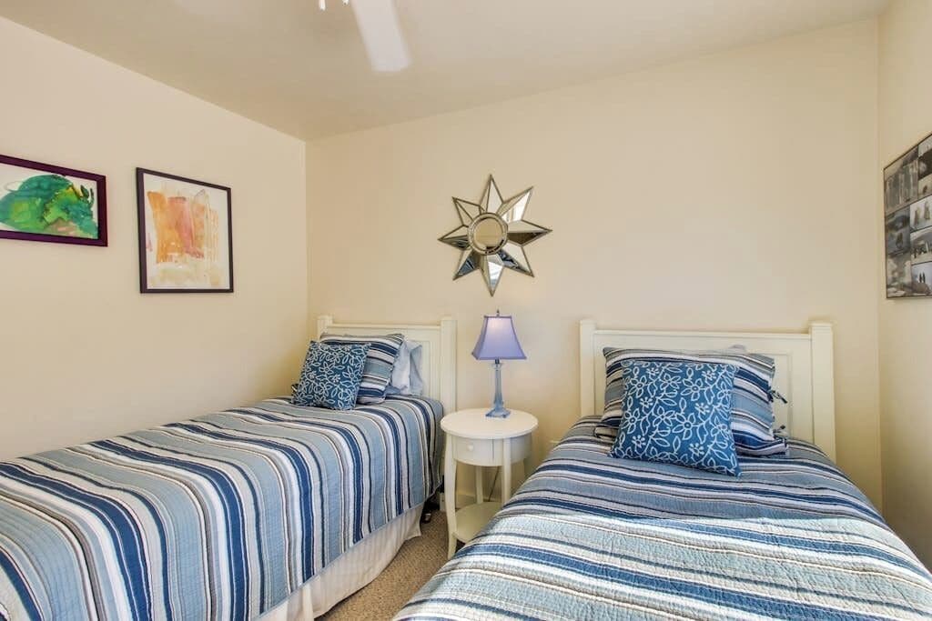 A bedroom with two beds, a nightstand, and wall art.