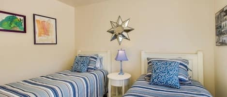 A bedroom with two beds, a nightstand, and wall art.