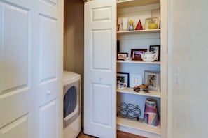 A laundry room with a washing machine and an open shelving unit with various items. - Lovely Mountain View Townhome with Shared Seasonal Hot Tub and Pool Near Downtown Moab (Moab)