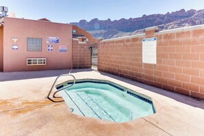 A swimming pool with a metal ladder, surrounded by a brick wall with a caution sign, and a building with various signs. - Lovely Mountain View Townhome with Shared Seasonal Hot Tub and Pool Near Downtown Moab (Moab)