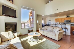 A spacious living room with a fireplace, a sofa, a coffee table, and a television. - Lovely Mountain View Townhome with Shared Seasonal Hot Tub and Pool Near Downtown Moab (Moab)