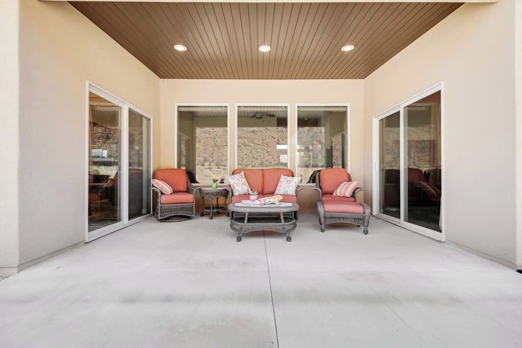 An outdoor patio area with wicker furniture and glass doors leading to a covered space.