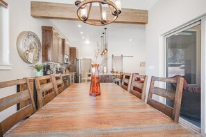 A dining area with a long wooden table, wooden chairs, a central vase, and a chandelier. - Spacious 3 Bedroom Moab Home with Hot Tub and Stunning Canyon Views (Moab)