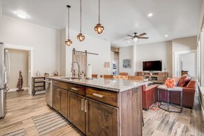 A modern kitchen with wooden cabinets, a central island, pendant lighting, and a ceiling fan. - Spacious 3 Bedroom Moab Home with Hot Tub and Stunning Canyon Views (Moab)