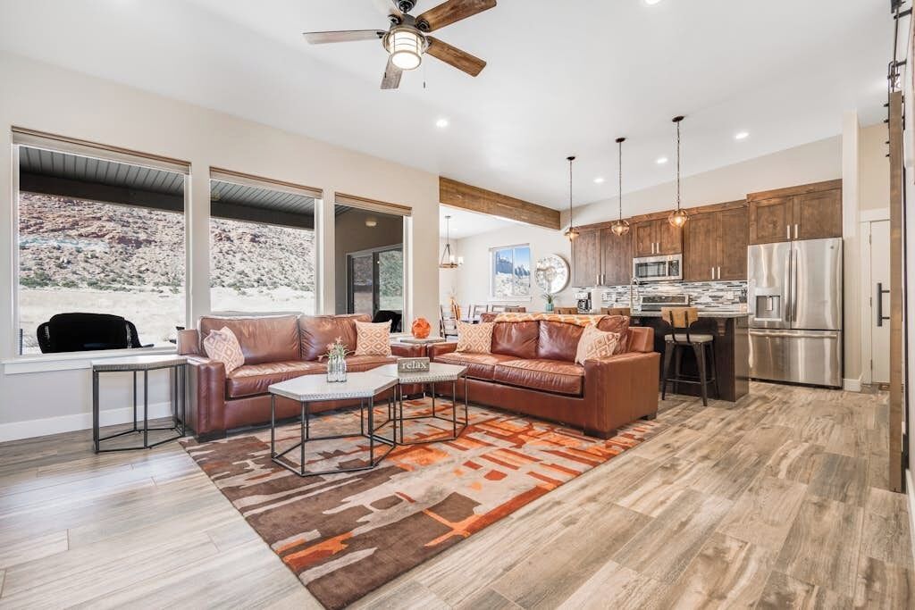 A modern kitchen with stainless steel appliances, a dining area with a leather couch, and large windows offering a view of the desert.