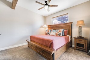 Une chambre à coucher avec un lit en bois, un ventilateur de plafond, une table de chevet avec une lampe et une fenêtre donnant sur un beau paysage.