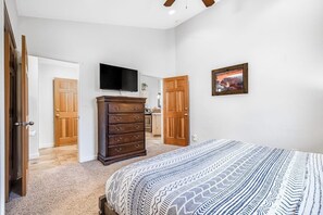 A bedroom with a bed, dresser, TV, and doors leading to other rooms. - Contemporary Condo near Parks and Downtown Moab with Pool & Hot Tub (Moab)