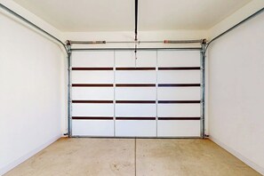 A garage with a metal door, white walls, and a concrete floor. - Tranquil Home with Amazing Views and Great Location - Close to Arches National Park (Moab)