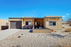 A modern two-story building with a garage, a covered patio, and a gravel driveway. - Tranquil Home with Amazing Views and Great Location - Close to Arches National Park (Moab)