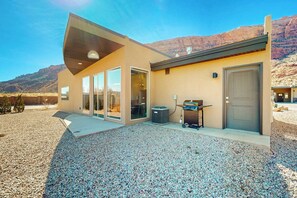 A modern building with a flat roof, large glass doors, and a gravel driveway. - Tranquil Home with Amazing Views and Great Location - Close to Arches National Park (Moab)