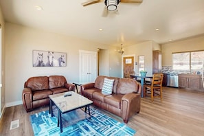 A spacious living area with leather sofas, a coffee table, and a dining table with chairs. - Tranquil Home with Amazing Views and Great Location - Close to Arches National Park (Moab)